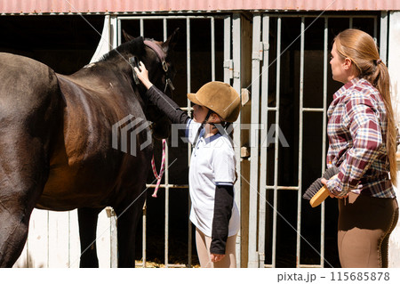 Child and woman grooming a horse Child and woman grooming a horse 115685878