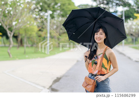 Sun protection with style a cheerful Asian woman with an umbrella in the sunshine. Sun protection with style a cheerful Asian woman with an umbrella in the sunshine. 115686299