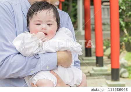 【父親に抱かれお宮参りの赤ちゃんと赤い鳥居】 115686968