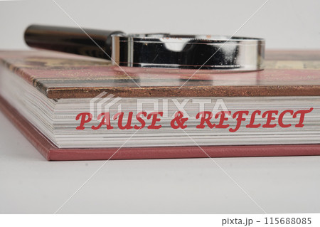 Pause and reflect word on the end of the book with a magnifying glass on top on a white background Pause and reflect word on the end of the book with a magnifying glass on top on a white background 115688085