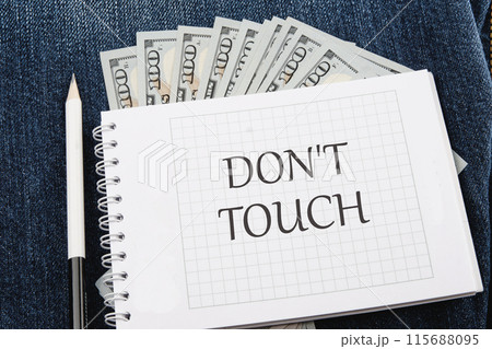 Words DO NOT TOUCH written on a checkered notebook in a composition with dollars bills and a pencil Words DO NOT TOUCH written on a checkered notebook in a composition with dollars bills and a pencil 115688095