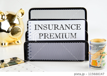 INSURANCE PREMIUM concept text. INSURANCE PREMIUM written on a blank sheet in a composition with a piggy bank and a roll of dollars INSURANCE PREMIUM concept text. INSURANCE PREMIUM written on a blank sheet in a composition with a piggy bank and a roll of dollars 115688147