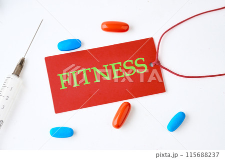Fitness, healthy lifestyle concept. A word FITNESS written on a red card on a light background with pills in the composition Fitness, healthy lifestyle concept. A word FITNESS written on a red card on a light background with pills in the composition 115688237
