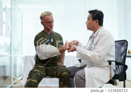 Doctor Examining Injured Arm of Soldier Doctor Examining Injured Arm of Soldier 115688723