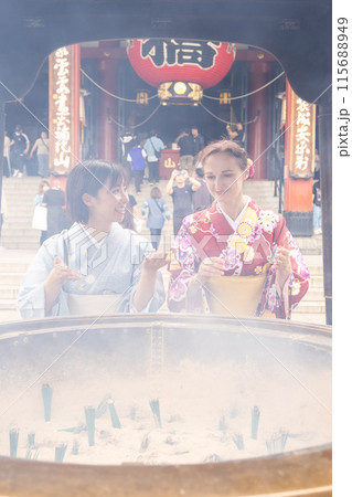 浅草寺で常香炉の煙を浴びる着物姿の外国人女性と案内する日本人女性 浅草寺で常香炉の煙を浴びる着物姿の外国人女性と案内する日本人女性 115688949