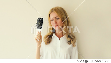Unhappy disappointed young woman with hair loss condition, showing hair brush, unhealthy hair Unhappy disappointed young woman with hair loss condition, showing hair brush, unhealthy hair 115689577