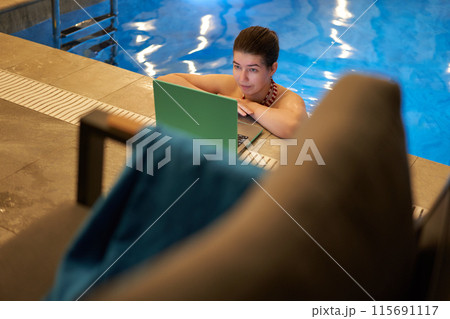 Woman Using Laptop by Swimming Pool Edge Woman Using Laptop by Swimming Pool Edge 115691117