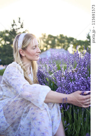 portrait of a young blonde woman in a pastel chiffon dress among lavender bushes 115691573