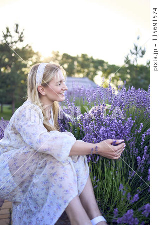 portrait of a young blonde woman in a pastel chiffon dress among lavender bushes 115691574
