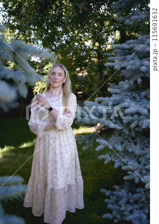 portrait of a young blonde girl in a pastel chiffon dress near a blue Christmas tree portrait of a young blonde girl in a pastel chiffon dress near a blue Christmas tree 115691632
