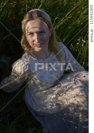 portrait of a young blonde woman in a pastel chiffon dress in a field of golden grass portrait of a young blonde woman in a pastel chiffon dress in a field of golden grass 115691805