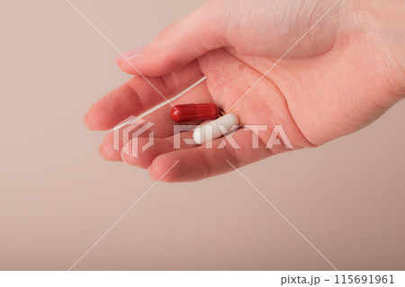 Female hand holding the capsules on pink background. Fingers holding pills, closeup. Concept of health care, dietary supplements, vitamins, treatment of depression and diseases. High quality photo Female hand holding the capsules on pink background. Fingers holding pills, closeup. Concept of health care, dietary supplements, vitamins, treatment of depression and diseases. High quality photo 115691961