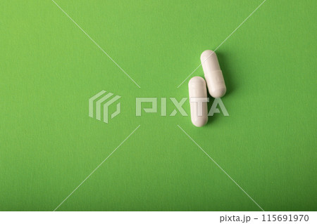Pills. Medical pills and capsules. Isolated on a green background. An allergy pill, antibiotics, supplements. Medicine, healthcare concept. Virus(viral) and flu diseases. High quality photo Pills. Medical pills and capsules. Isolated on a green background. An allergy pill, antibiotics, supplements. Medicine, healthcare concept. Virus(viral) and flu diseases. High quality photo 115691970