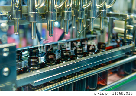 Glass bottles in a conveyor belt on a high quality automatic vertical filling machine. In the factory production line 115692019