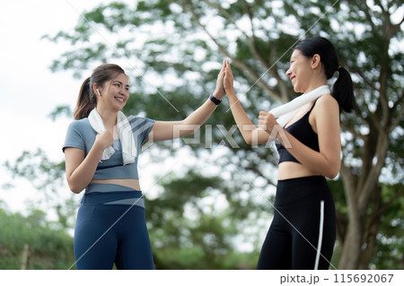 Two Friends Celebrating After a Morning Run with High Five in Outdoor Park Two Friends Celebrating After a Morning Run with High Five in Outdoor Park 115692067