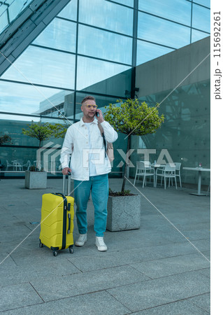 Young Caucasian male passenger in stylish casual clothes using smartphone and laptop keyboard, sit has training online meeting on laptop computer in airline lounge wait transit international airport Young Caucasian male passenger in stylish casual clothes using smartphone and laptop keyboard, sit has training online meeting on laptop computer in airline lounge wait transit international airport 115692261
