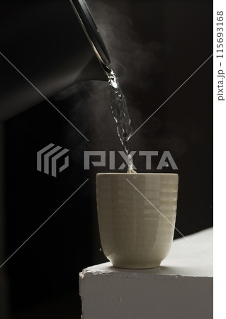 A serene scene with steam rising from a cup on a stark background. 115693168