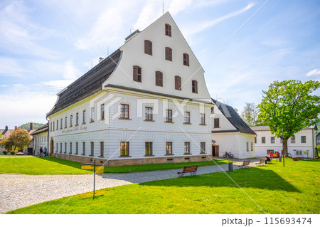 A view of the historic paper mill building in Velke Losiny, Czechia. The building is white with a distinctive roof, showcasing its traditional design. A view of the historic paper mill building in Velke Losiny, Czechia. The building is white with a distinctive roof, showcasing its traditional design. 115693474