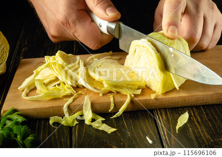 Chef hands slicing fresh cabbage with a knife on a cutting board for vitamin salad. Diet menu for breakfast or dinner Chef hands slicing fresh cabbage with a knife on a cutting board for vitamin salad. Diet menu for breakfast or dinner 115696106