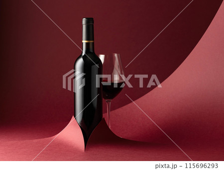 Bottle and glass of red wine on a red background. Bottle and glass of red wine on a red background. 115696293