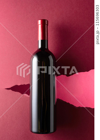 Bottle of red wine on a dark red background. Bottle of red wine on a dark red background. 115696303