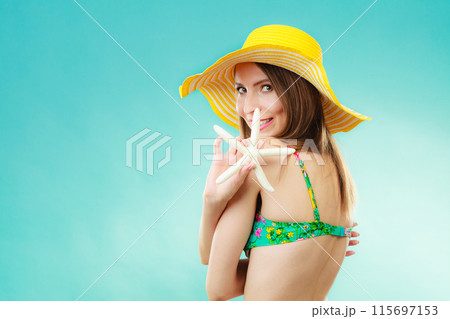 Woman in yellow hat holding white shell 115697153