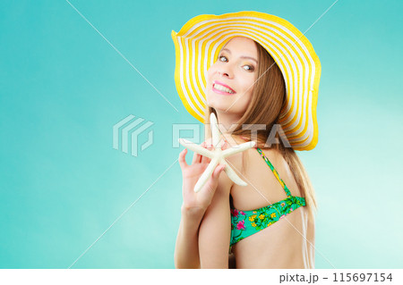 Woman in yellow hat holding white shell 115697154