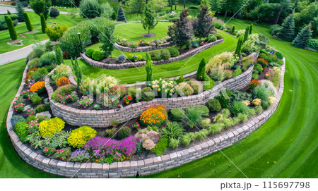 Landscaped home garden with terraces and rocks, beautiful design of luxury house back yard, stone retaining walls in summer. Concept of landscaping, backyard, plants, flower Landscaped home garden with terraces and rocks, beautiful design of luxury house back yard, stone retaining walls in summer. Concept of landscaping, backyard, plants, flower 115697798