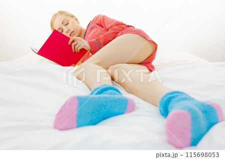 Woman relaxing in bed reading book Woman relaxing in bed reading book 115698053