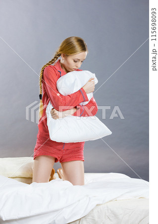 Sad depressed girl in bed gripping pillow Sad depressed girl in bed gripping pillow 115698093