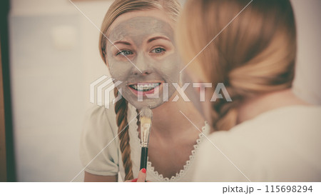 Woman with grey clay mud mask on her face 115698294