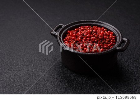 Spice, allspice peas in red or pink color in a bowl on a black concrete background 115698669