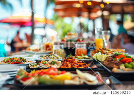 Beachside dining setup featuring a variety of food platters under a shaded canopy 115699210