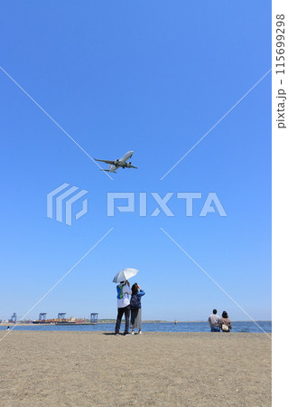 頭上を飛ぶ旅客機を眺める人たち 着陸進入する旅客機 頭上を飛ぶ旅客機を眺める人たち 着陸進入する旅客機 115699298