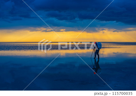 Photographer capturing a stunning sunset over calm reflective water Photographer capturing a stunning sunset over calm reflective water 115700035