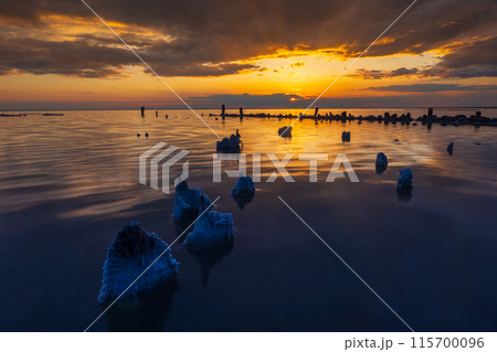 Stunning sunset over calm sea with rocky formations Stunning sunset over calm sea with rocky formations 115700096