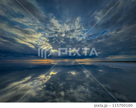 Dramatic sky reflected in calm ocean waters at sunset 115700100