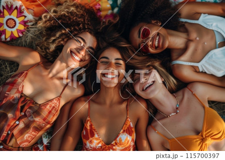 Group of diverse women lying on grass smiling together outdoors 115700397