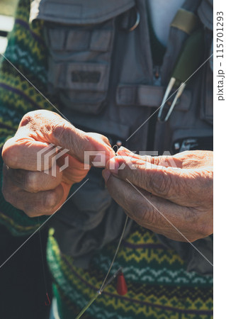 仕掛け作りをする70代の釣り人 115701293