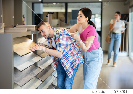 Interracial couple discussing choice of laminate flooring in building hypermarket Interracial couple discussing choice of laminate flooring in building hypermarket 115702032