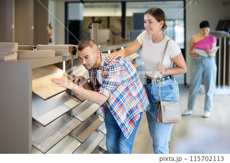 Interested couple selecting laminate floorboards in building hypermarket Interested couple selecting laminate floorboards in building hypermarket 115702113