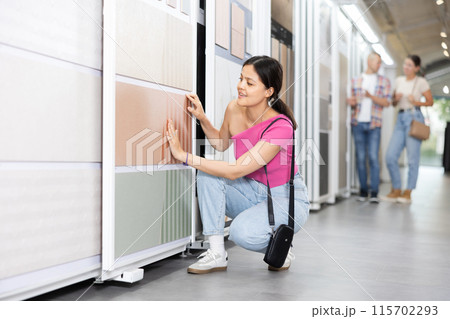 Asian woman examining tile samples on sliding display rack in store Asian woman examining tile samples on sliding display rack in store 115702293