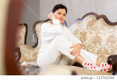 Relaxed young brunette sitting on soft antique sofa at home Relaxed young brunette sitting on soft antique sofa at home 115702300