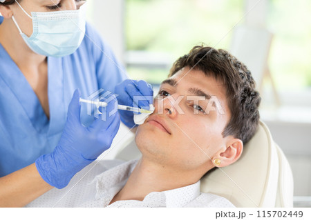 Young man having face care by means of injection in aesthetic clinic 115702449