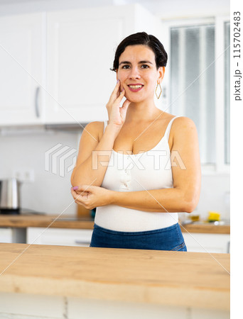 Portrait of girl housewife standing at home kitchen Portrait of girl housewife standing at home kitchen 115702483