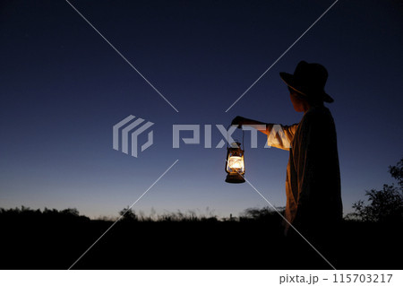 夕闇でランタンをかざす男性 115703217