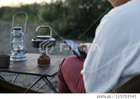 キャンプでスマホを見る男性 115703545