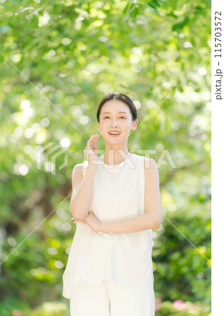 新緑の中で頬を触る女性のビューティー 115703572