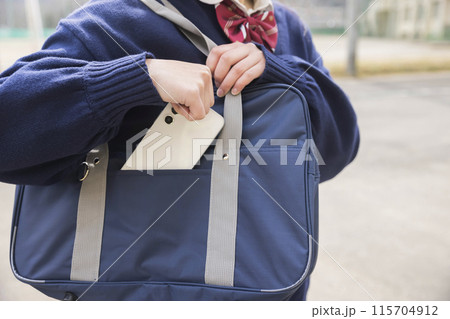 スマホをスクールバッグにしまう女子高生手元 スマホをスクールバッグにしまう女子高生手元 115704912