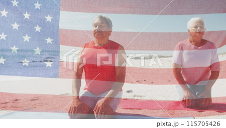 Image of flag of united states of america over senior biracial couple meditating on beach 115705426